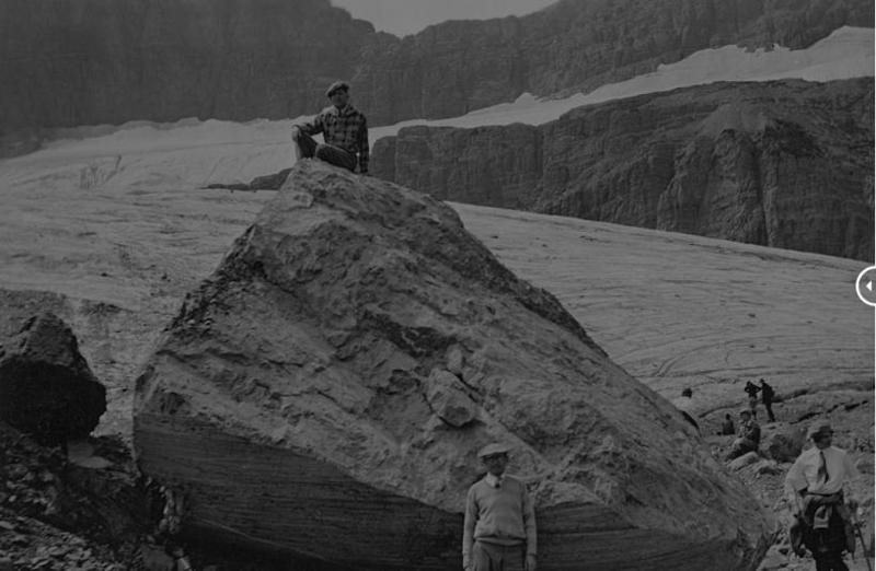 a man sitting on a rock observing a glacier